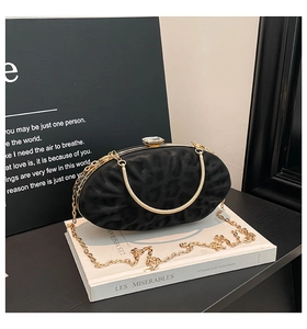 Detail of black suede oval clutch bag with leopard embossing and gold chain strap
