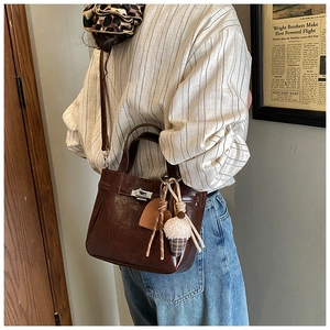 Detail of a dark brown vintage bucket bag with silver lock and plush heart charm decoration
