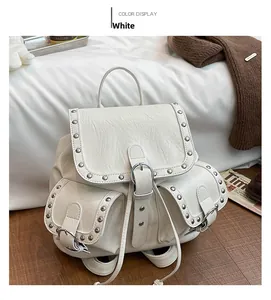 Vue détaillée du sac à dos blanc avec clous argentés et boucles métalliques sur tissu blanc