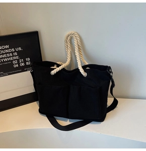 Detailed macro view of black corduroy tote bag showing rope handles and front pockets