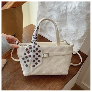 Detail view of cream woven tote bag with brown polka dot scarf and leather strap detail