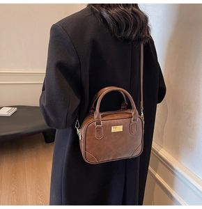 Detailed view of dark brown retro crossbody bag with golden buckle and adjustable strap