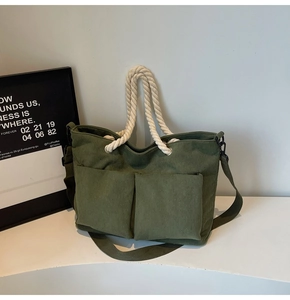 Detail view of dark green corduroy tote bag featuring large utility front pockets and rope handles