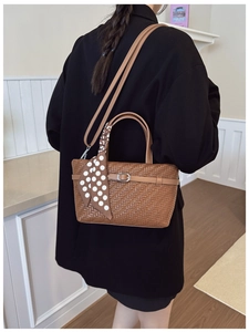 Detail of a brown woven texture handbag with polka dot silk scarf and silver buckle strap