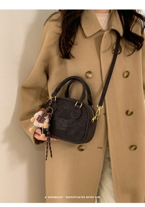 Detail of grey retro Boston bag featuring a plush sheep charm and gold-tone zippers