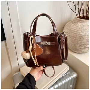 Detail of dark brown leather bucket bag with heart pendant and silver twist lock
