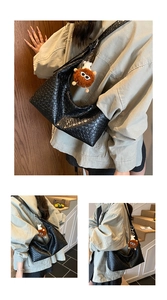Detail of black woven shoulder bag featuring a cute brown plush monster charm accessory