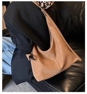 Gros plan détaillé du sac hobo en cuir marron avec surpiqûres blanches et forme souple