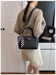 Detail of black woven handbag with polka dot scarf handle and silver buckle strap