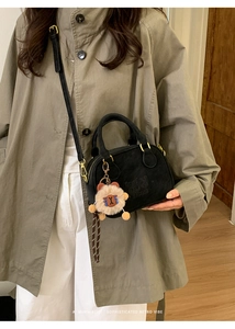 Detail of black bowling bag with LUCKY logo, gold hardware and plush bear charm accessory