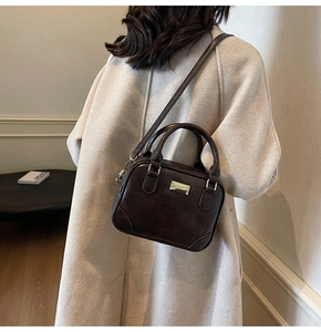Detail of dark brown vintage satchel bag worn over a beige wool coat for office style