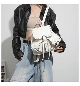 Détail du sac à dos en similicuir blanc avec rivets argentés et fermeture magnétique