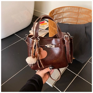Detail of retro dark brown bucket bag with silver twist lock and heart pendant