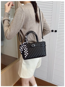 Detail of black woven shoulder bag with polka dot scarf handle and silver buckle accent