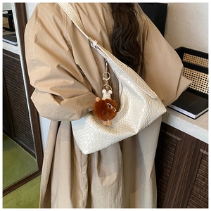 Detail of white woven textured crescent bag with cute brown plush bear charm accessory
