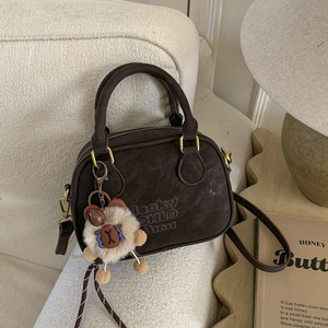 Detail of vintage brown suede bowling bag with embossed logo and fuzzy charm