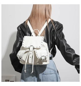 Détail d'un sac à dos blanc en similicuir avec clous argentés et lanières à boucles