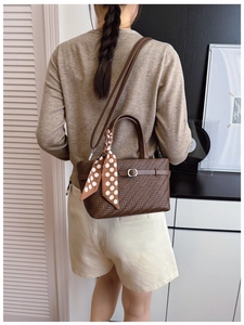 Detail view of brown woven PU leather handbag with silk scarf on a model's shoulder