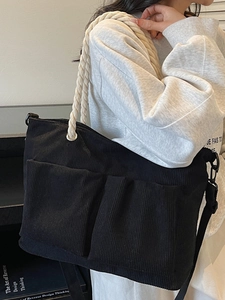 Large black corduroy tote bag with dual front pockets and cream cotton rope handles