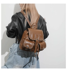 Vue arrière du mannequin portant un sac à dos en cuir marron vintage avec rivets en métal