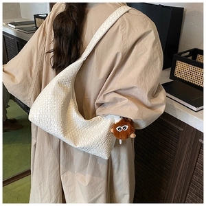 Detail of white woven PU leather tote bag with brown plush pendant on trench coat