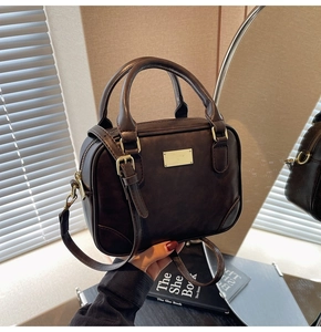 Close-up of a vintage dark brown handbag with gold hardware and a detachable strap