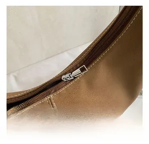 Gros plan sur la fermeture éclair argentée et coutures sur un sac cabas en simili cuir
