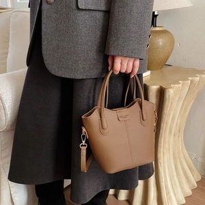 Detailansicht der braunen Bucket Bag aus Leder mit Narbenstruktur und Logo-Prägung
