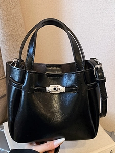 Minimalist black shiny bucket bag with silver metal buckle and dual handles in soft light
