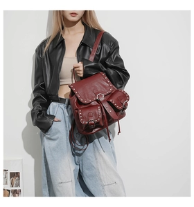 Détail d'un sac à dos vintage bordeaux avec rivets argentés porté par un mannequin