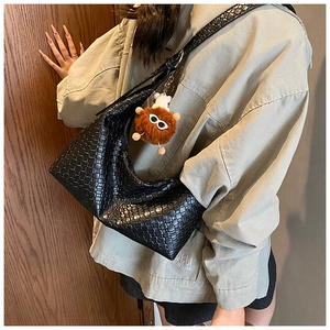 Detailed close-up of a black woven leather hobo bag with cute furry ball accessory