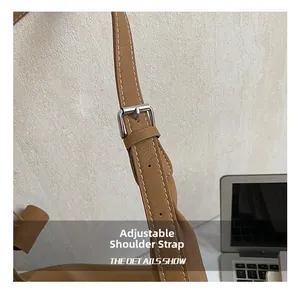 Détail de la bandoulière réglable avec boucle argentée sur un sac cabas en cuir marron