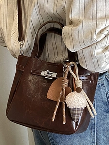 Brown oil wax leather bucket bag with silver lock and plush heart charm accessory