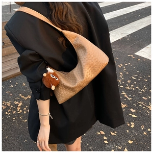 Close-up of tan woven leather Hobo bag with a cute brown plush bear charm pendant