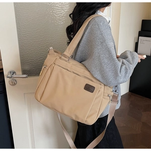 Détail d'un grand sac fourre-tout en nylon kaki avec patch logo en cuir et poche zippée externe