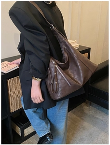 Détail d'un grand sac cabas en cuir marron foncé avec texture lisse et poches zippées en métal