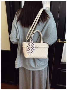 Detailed macro view of cream woven texture handbag with polka dot silk scarf handle