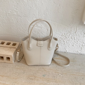 Detailansicht der beigefarbenen Beuteltasche mit Lychee-Maserung und Gold-Hardware