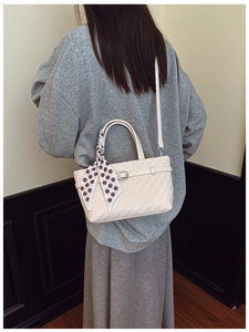 Detail of white woven crossbody bag with polka dot scarf and silver metal buckle