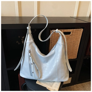 Détails d'un grand sac hobo bleu clair en cuir avec fermeture éclair et rivets décoratifs