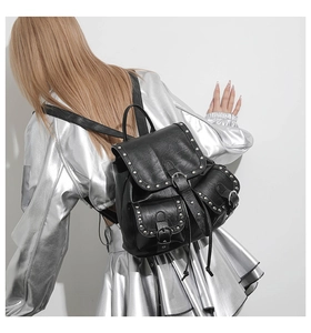 Détail du sac à dos en similicuir noir avec clous argentés et poches à boucles multiples