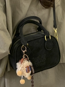 Vintage black suede bowling bag with gold hardware and plush sheep charm on model