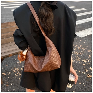 Detail of a brown woven leather tote bag with a plush charm on the shoulder