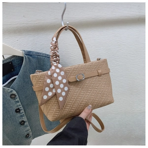 Detail of khaki woven handbag showing textured pattern and polka dot scarf decoration