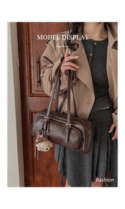Detail of vintage brown leather bowling bag featuring side zipper and bear charm accessory