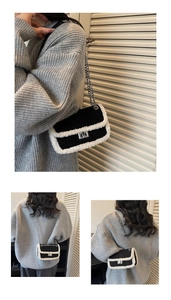Detailed view of women's black and white contrast crossbody bag with metal chain strap