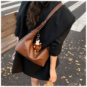 Detail of dark brown woven leather texture on hobo bag with a plush monster charm