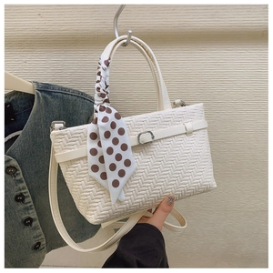 Detail of white woven tote bag with silver buckle and brown polka dot silk scarf