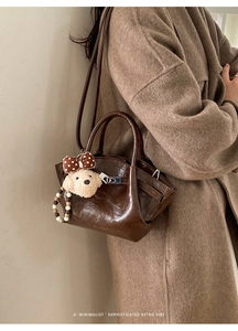 Detailed side view of dark brown leather bucket bag with cute plush puppy charm