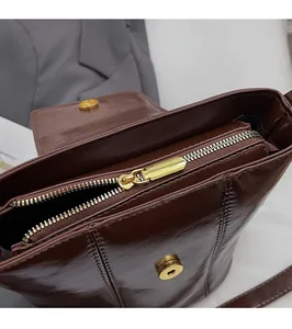 Detailed close-up of dark brown leather bucket bag with gold zipper and magnetic closure